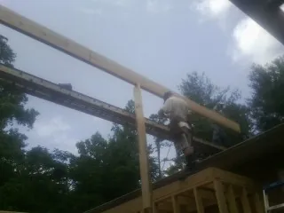 Carpenter setting a ridge beam over a new addition frame — Ice Dam Removal by Roofing Brothers in Ward
