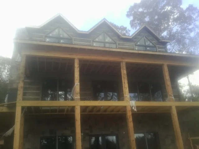 Dormers and porch framing on a large log home under construction — Roof Coating work by our crew in Ward