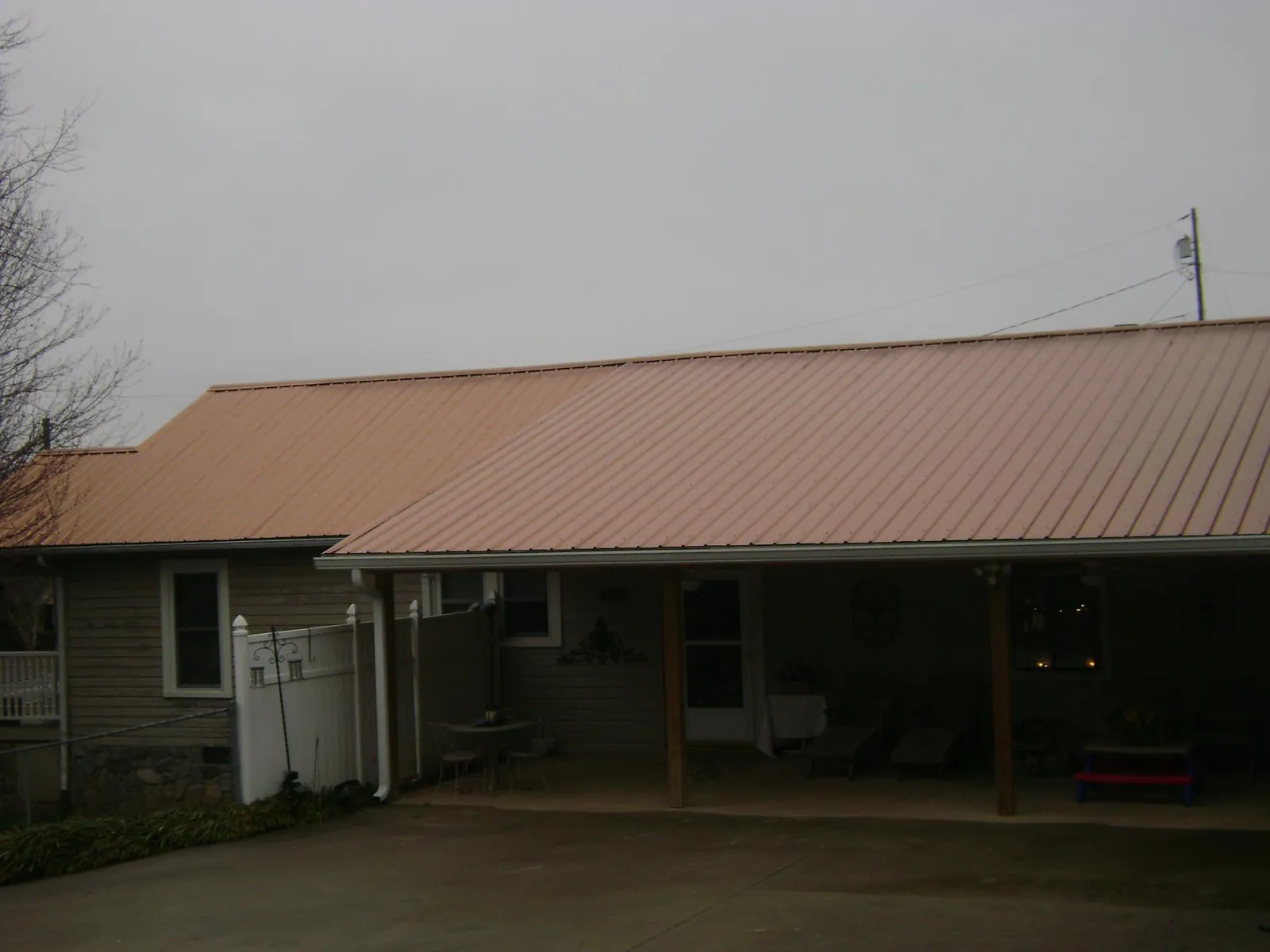 Copper toned metal roof over a wide covered patio in Ward