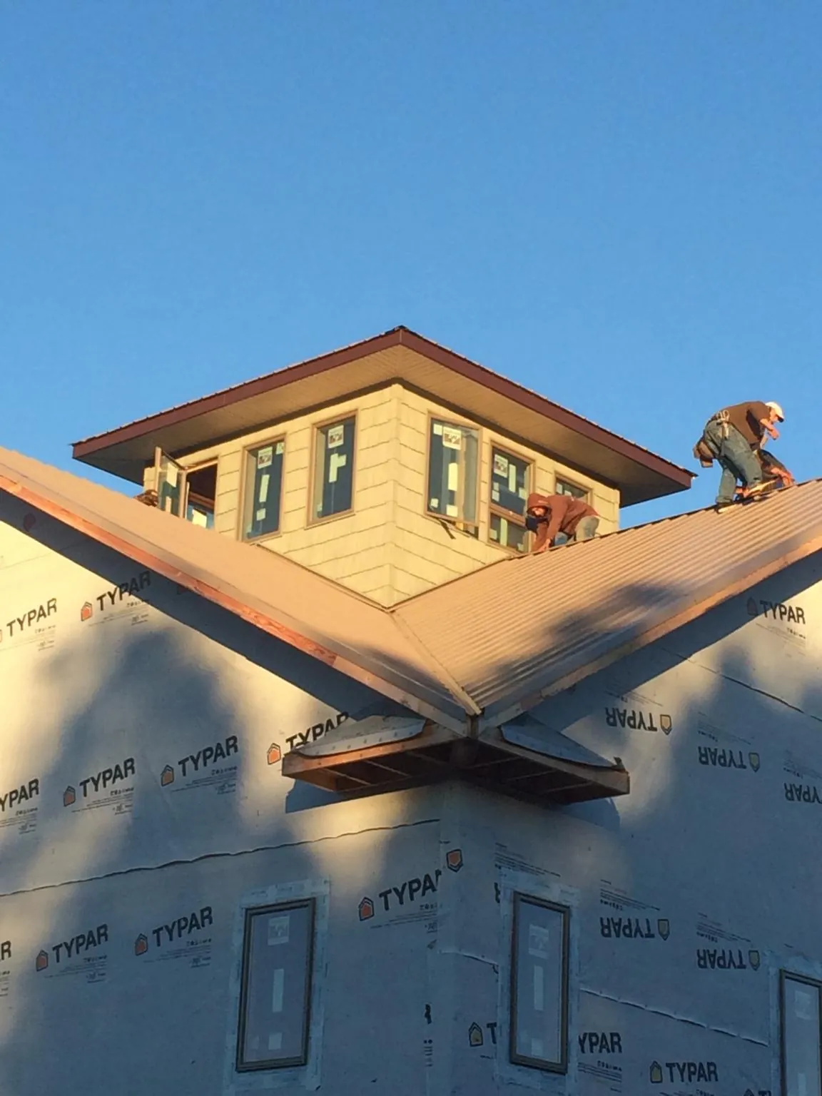Roofers working around a rooftop cupola on a new metal roof at sunset — Roof Waterproofing in Ward by Roofing Brothers